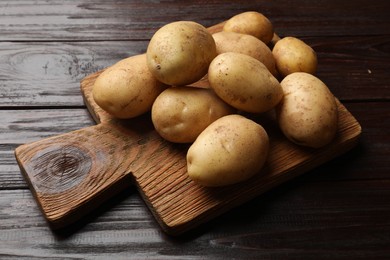 Photo of Raw fresh potatoes and cutting board on wooden table