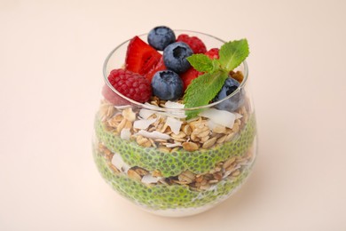 Photo of Tasty oatmeal with chia matcha pudding and berries on beige background. Healthy breakfast