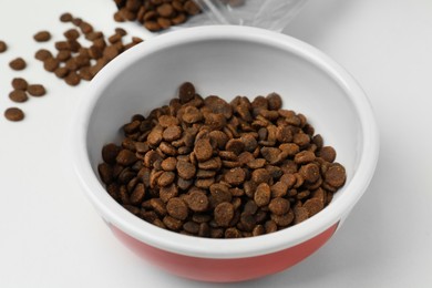 Photo of Feeding bowl with dry cat food on white background, closeup
