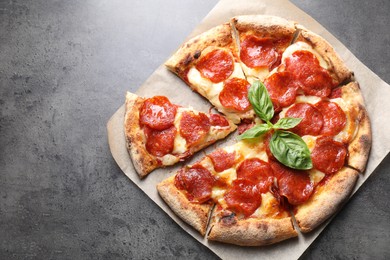 Tasty pepperoni pizza with basil on grey table, top view. Space for text