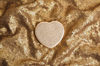 Stylish heart shaped cosmetic pocket mirror on gold fabric, top view