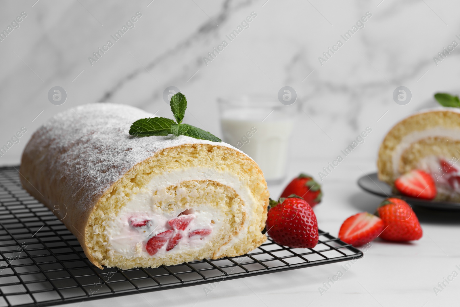 Photo of Delicious sponge cake roll with strawberries and cream on white table, space for text