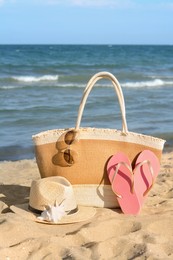 Photo of Stylish bag and other beach accessories near sea on sunny day