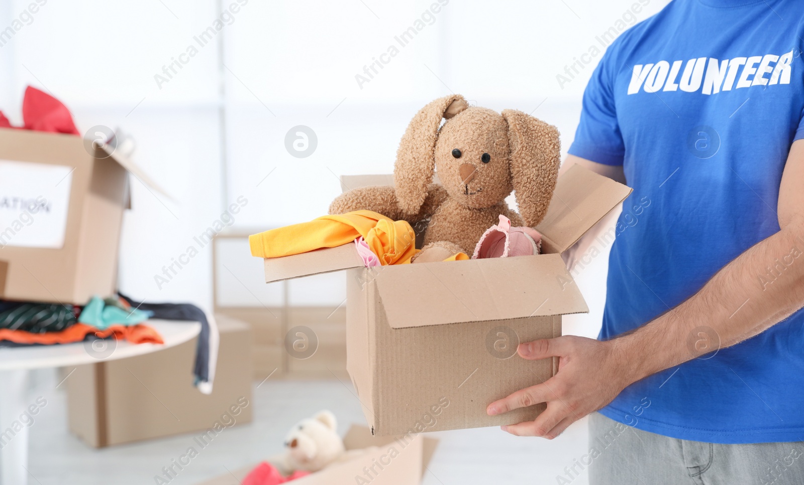 Photo of Male volunteer holding box with donations indoors. Space for text