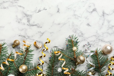 Shiny serpentine streamers, Christmas balls and fir branches on white marble background, flat lay. Space for text