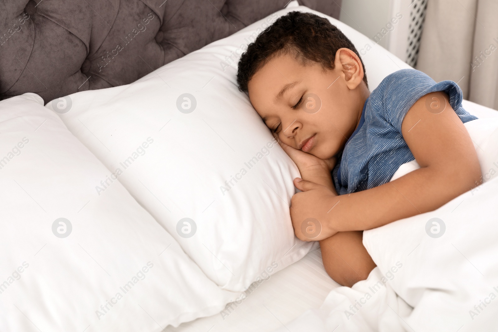 Photo of Cute little African-American boy sleeping in bed