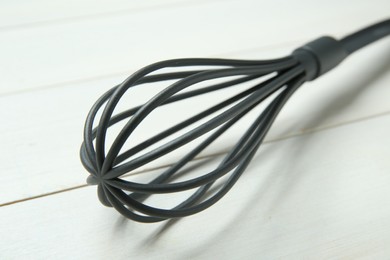 Photo of Plastic whisk on white wooden table, closeup