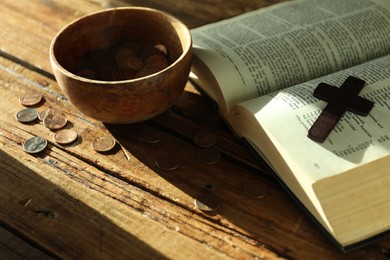 Donate and give concept. Bowl with coins, cross and Bible on wooden table