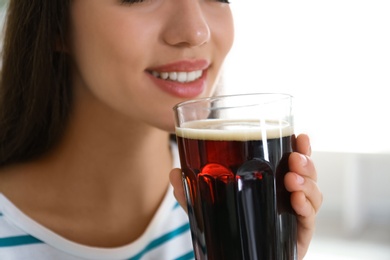 Photo of Young woman with cold kvass indoors, closeup. Traditional Russian summer drink