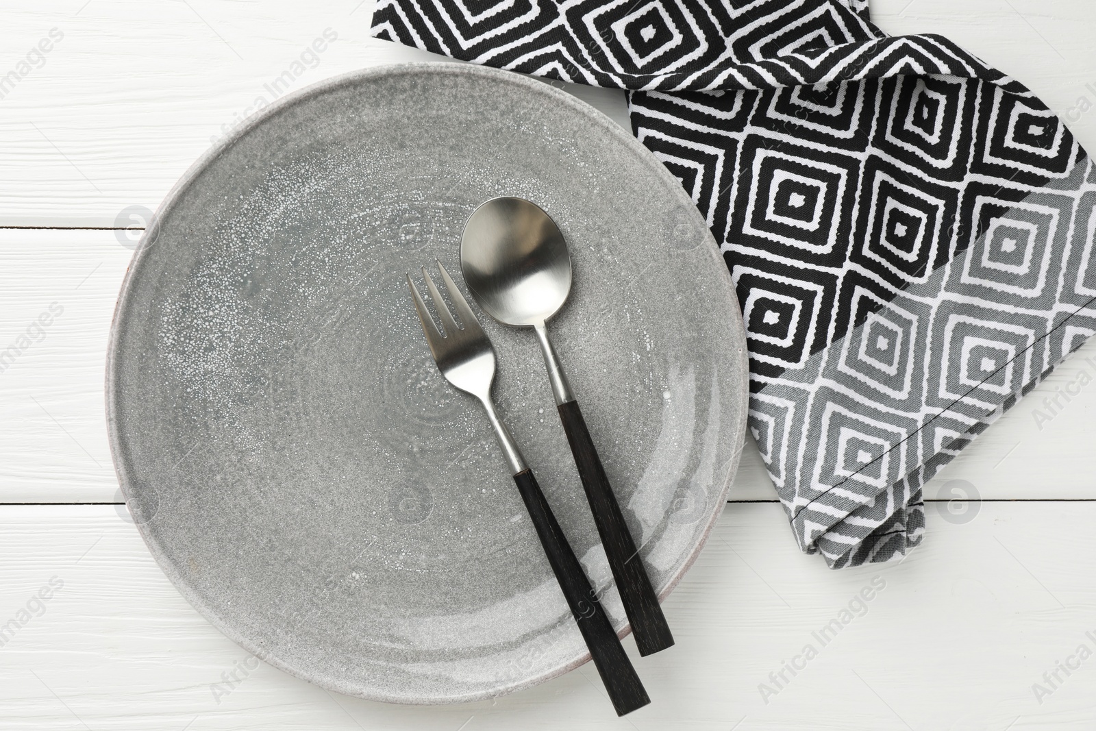 Photo of Stylish setting with cutlery, napkin and plate on white wooden table, top view