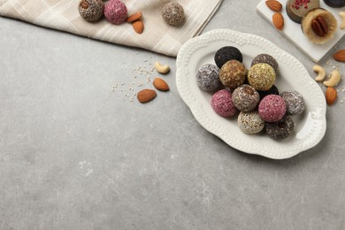 Different delicious vegan candy balls and nuts on grey table, flat lay. Space for text