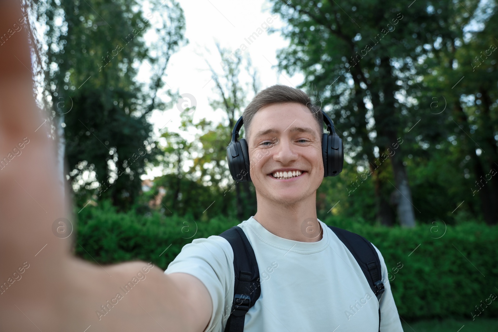 Photo of Smiling man in headphones taking selfie in park