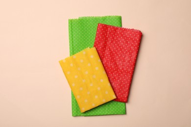 Photo of Colorful reusable beeswax food wraps on beige background, top view