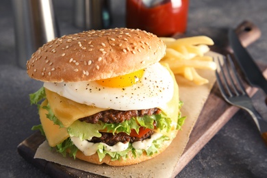 Tasty burger with fried egg on wooden board