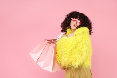 Photo of Happy young woman with shopping bags on pink background