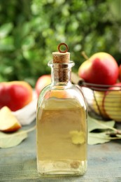 Natural apple vinegar and fresh fruits on blue wooden table