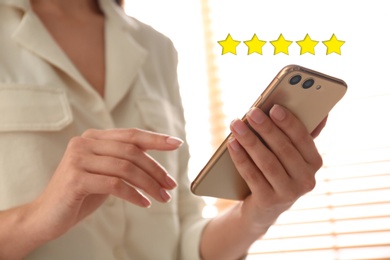 Image of Woman leaving review online via smartphone indoors, closeup. Five stars over gadget