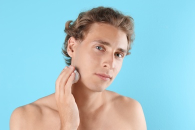 Photo of Young man applying shaving foam on color background