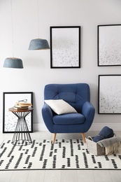 Beautiful artworks and comfortable armchair in stylish room. Interior design