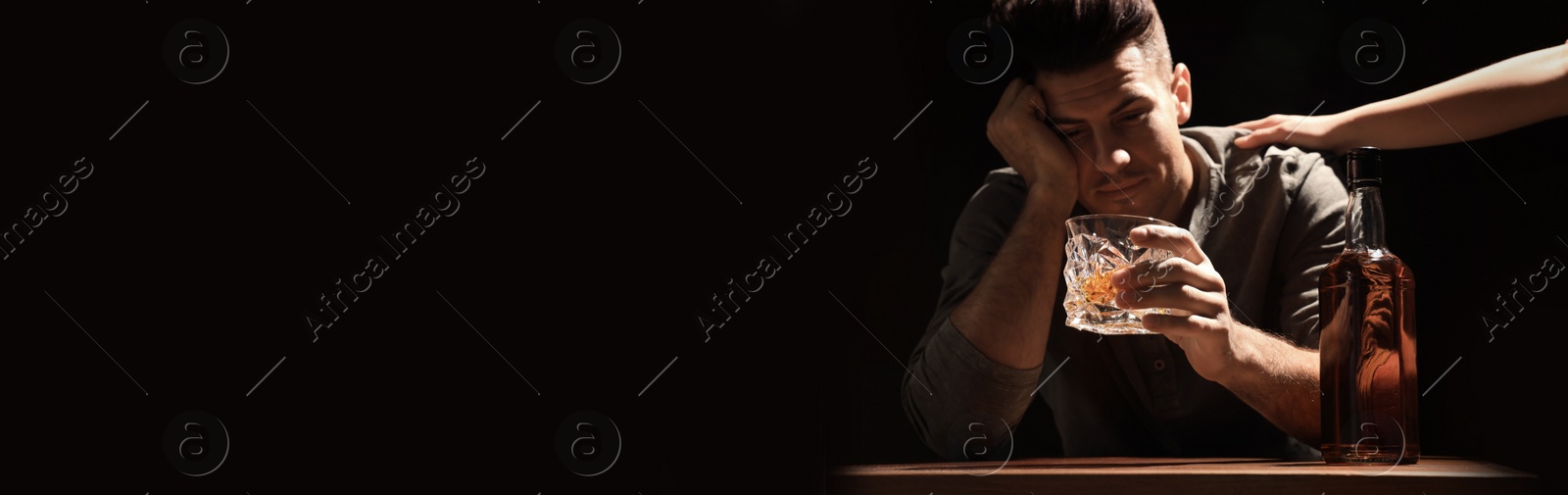 Image of Suffering from hangover. Man with glass of alcoholic drink at table against black background, selective focus. Banner design with space for text