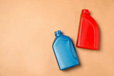 Motor oil in different canisters on light brown background, flat lay. Space for text