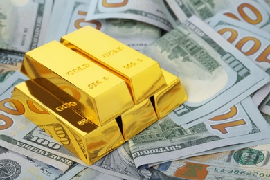 Photo of Precious shiny gold bars on dollar bills