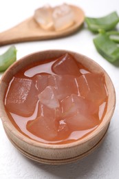 Aloe vera gel and slices of plant on white background, closeup