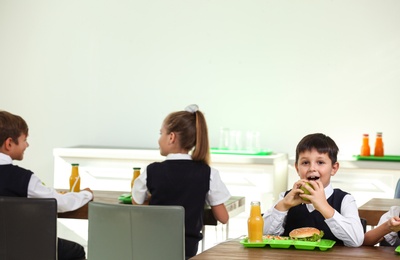 Photo of Happy children eating healthy food for lunch in school canteen