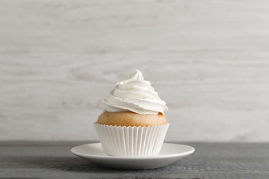 Delicious cupcake with cream on grey wooden table