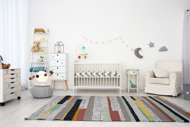 Photo of Cozy baby room interior with crib and armchair