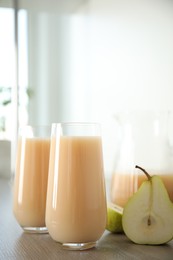 Tasty pear juice and cut fruit on wooden table