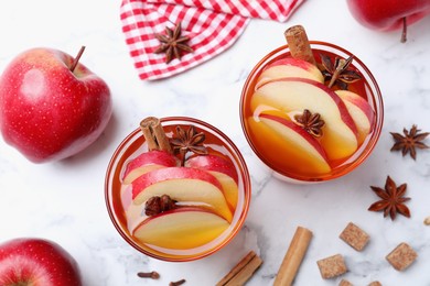 Photo of Aromatic hot mulled cider on white marble table, flat lay