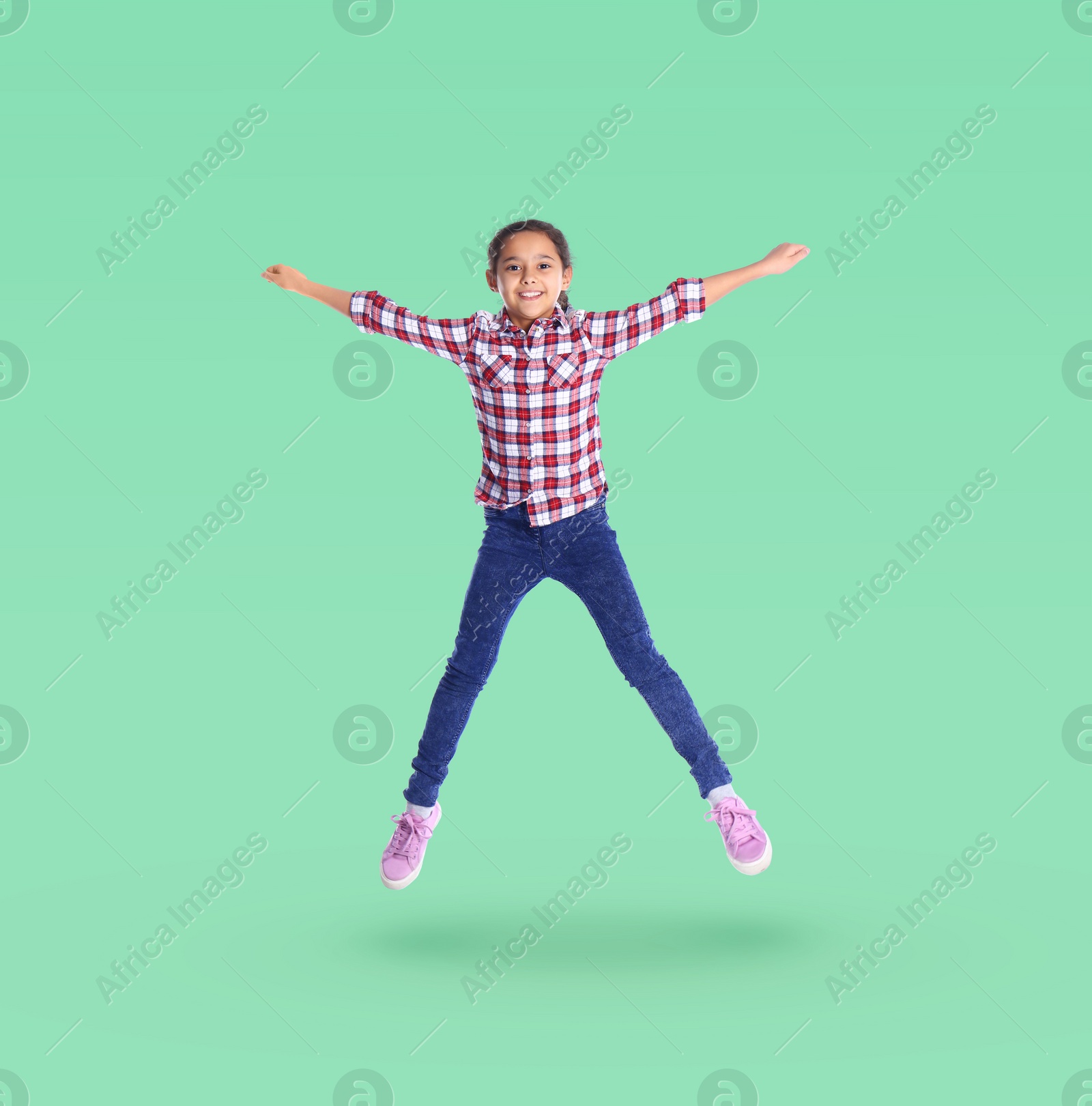 Image of Happy cute girl jumping on aquamarine background