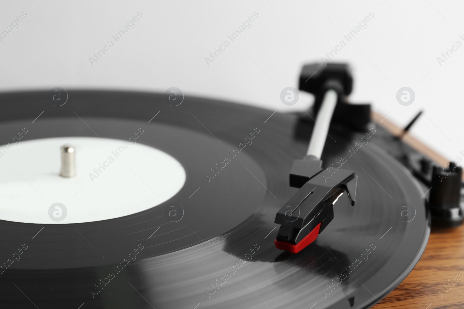 Photo of Vinyl record on turntable against light background, closeup