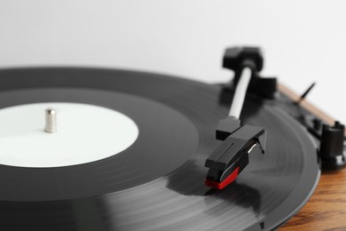 Photo of Vinyl record on turntable against light background, closeup