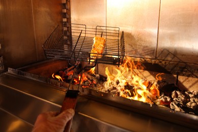 Photo of Chef cooking salmon fillet on grilling basket in oven, closeup
