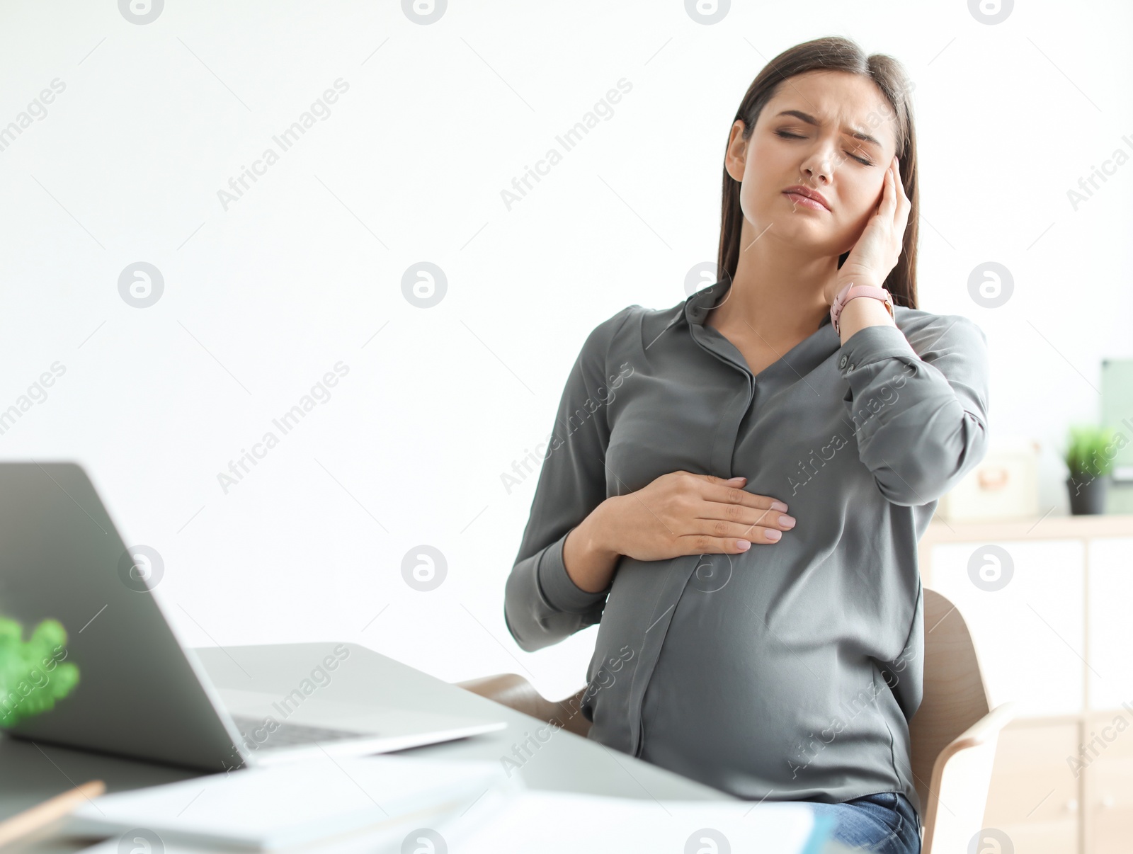 Photo of Pregnant woman suffering from headache at workplace