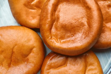 Many delicious baked patties on plate, top view