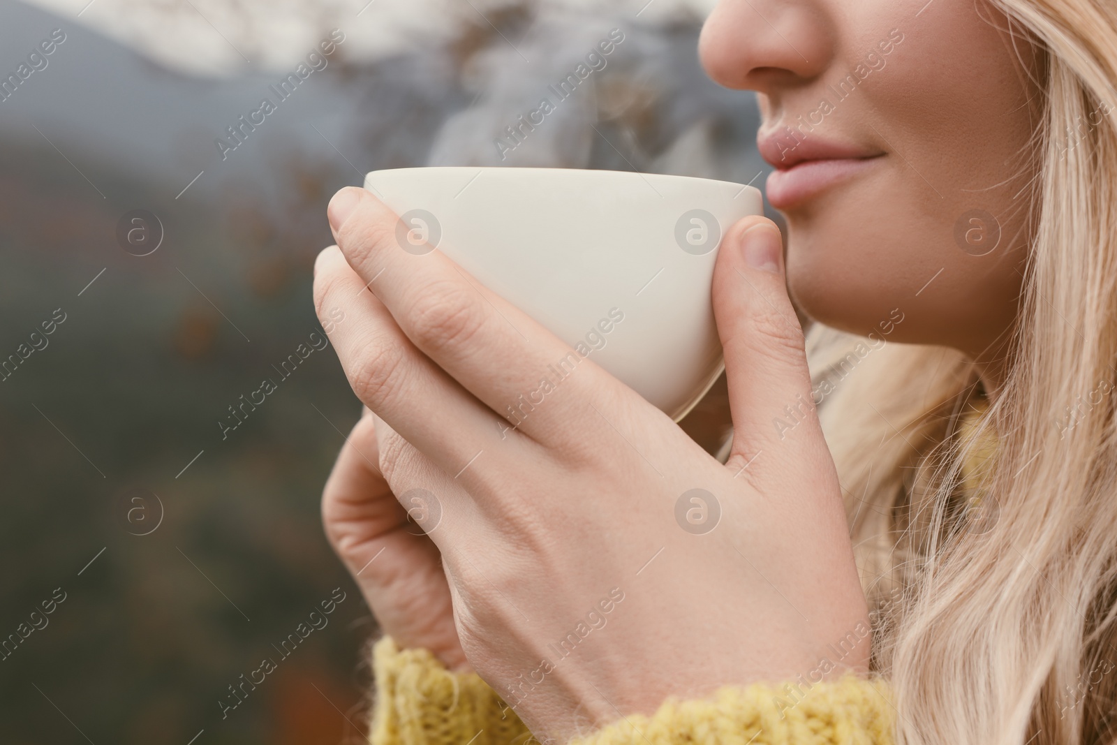 Photo of Young woman with cup of hot drink outdoors, closeup