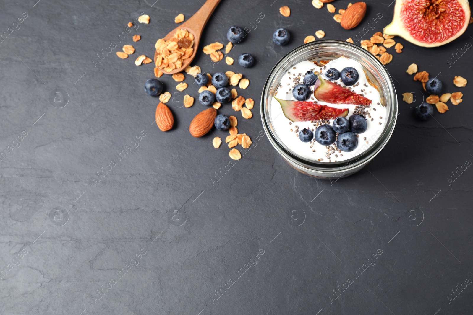 Photo of Healthy homemade granola with yogurt on dark grey table, flat lay. Space for text
