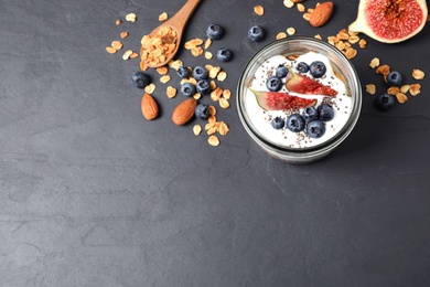 Healthy homemade granola with yogurt on dark grey table, flat lay. Space for text
