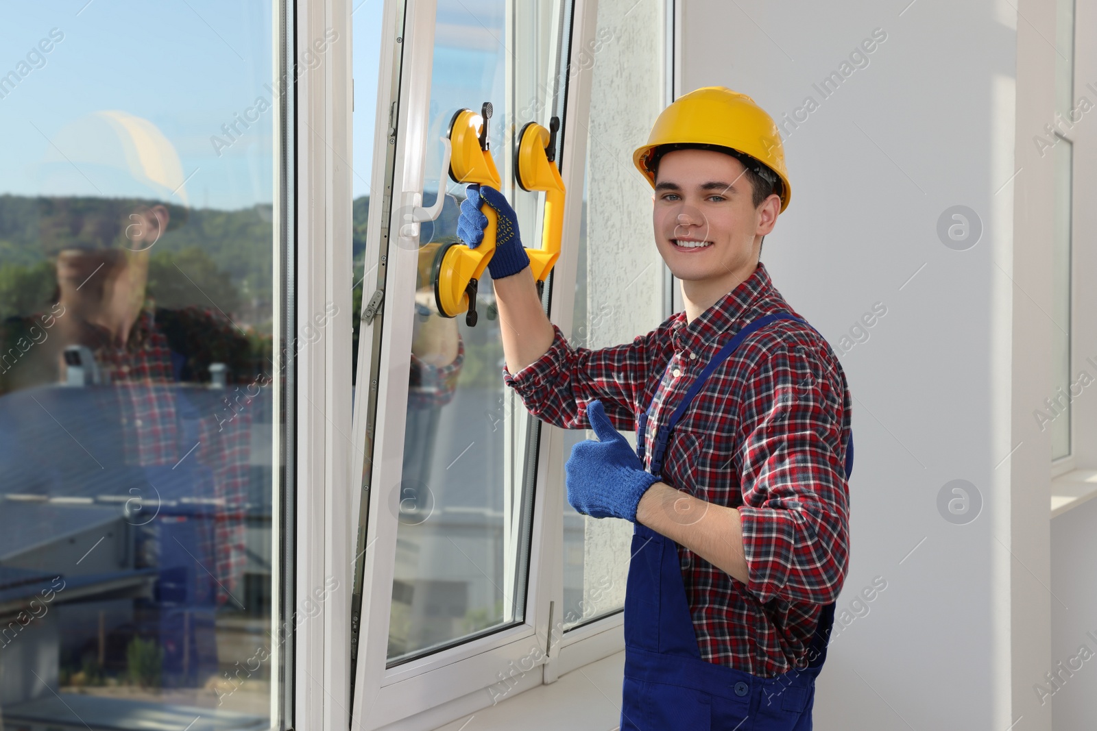 Photo of Worker using suction lifters during plastic window installation indoors