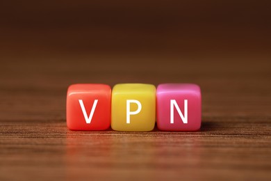Photo of Colorful plastic beads with acronym VPN on wooden table