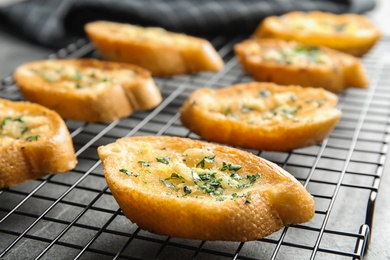 Baking rack with tasty homemade garlic bread on table, closeup