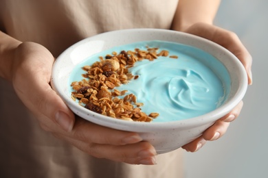 Woman holding bowl of spirulina smoothie, closeup