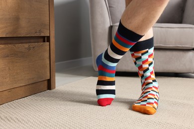 Man in different stylish socks indoors, closeup. Space for text