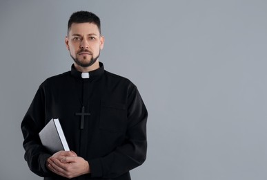 Photo of Priest with Bible on grey background, space for text