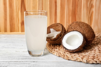 Glass of coconut water and fresh nuts on wooden table