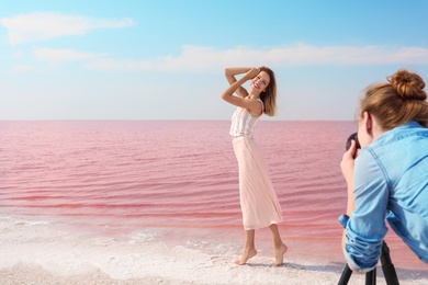 Photo of Female photographer taking pictures of model near pink lake
