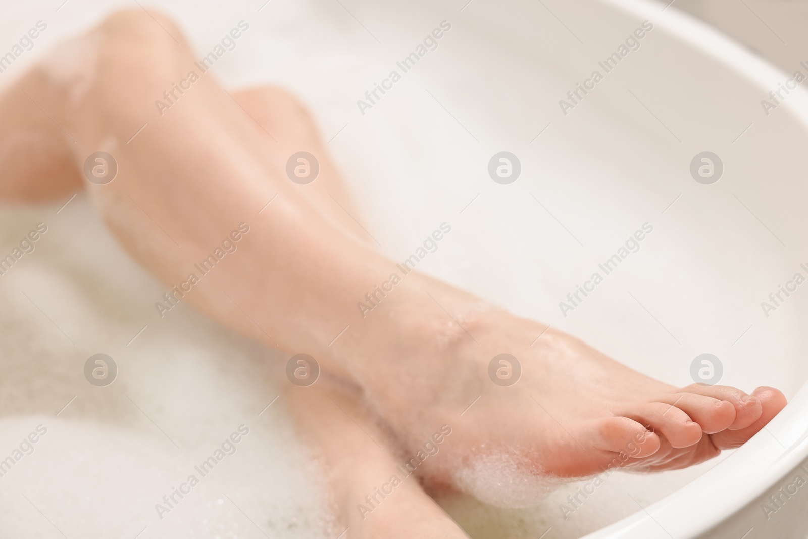 Photo of Woman taking bath with foam in tub, closeup